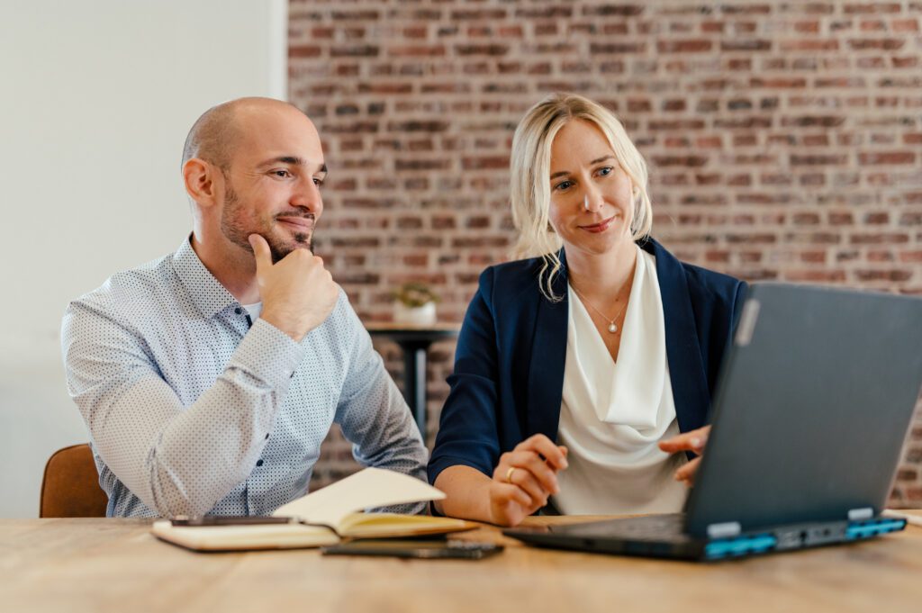 Zwei Personen prüfen gemeinsam das Reporting der Kampagne am Laptop